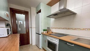 A kitchen with a microwave, refrigerator, stove, and a wooden countertop.