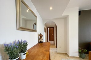 A hallway with a wooden table, two potted plants, a mirror, and a door leading to another room. - JAN001 Modern Spacious 2 Bedroom Apartment (Ayamonte)