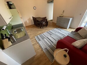 A compact living space with a kitchenette, dining area, and a red sofa.