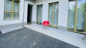 En byggnad med stora fönster, en röd stol och en balkong av betong.