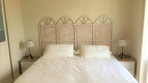 A bed with a white headboard and two bedside tables with lamps.