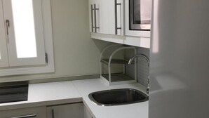 A modern kitchen with white cabinetry, a stainless steel sink, and a built-in microwave.