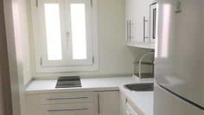 A compact kitchen with a built-in washing machine, a sink, and a window with a view.