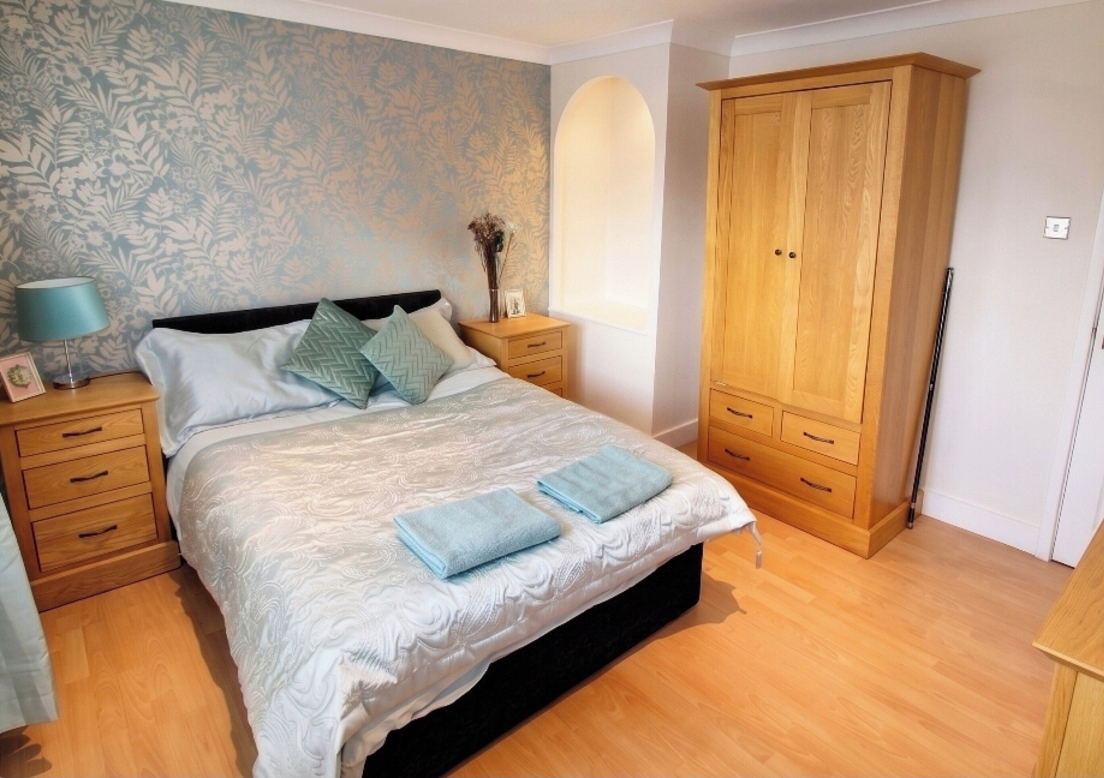 Quarto com cama, mesas de cabeceira, guarda-roupa e papel de parede floral.