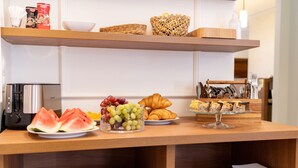 A breakfast buffet with various food items, including watermelon, grapes, croissants, and pastries. - Portal House Apartments (Kraków)