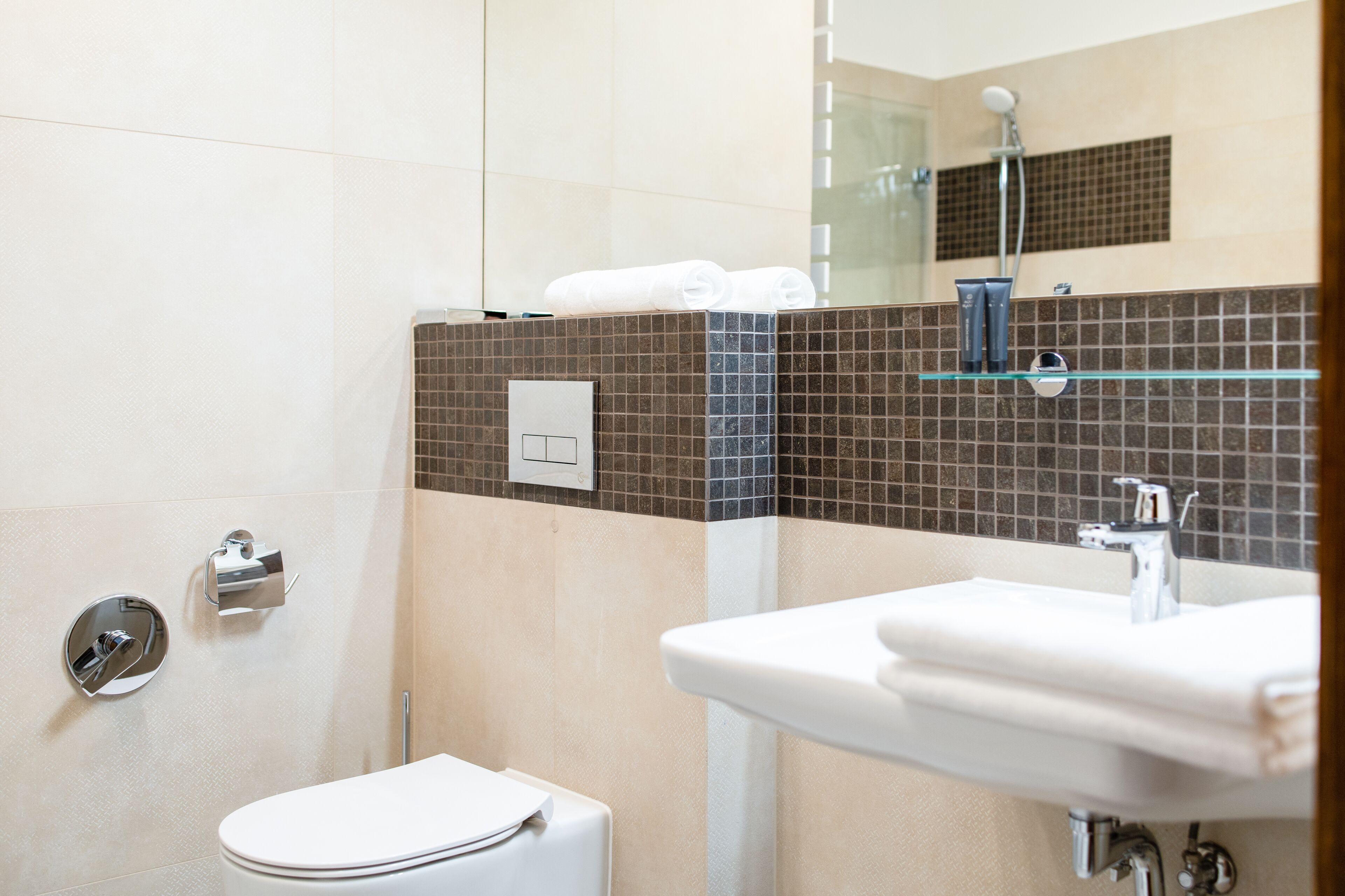 Een moderne badkamer met toilet, wastafel en douche.