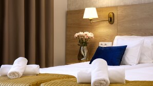 A hotel room with a bed, pillows, a vase with flowers, and a wall-mounted lamp. - Portal House Apartments (Kraków)