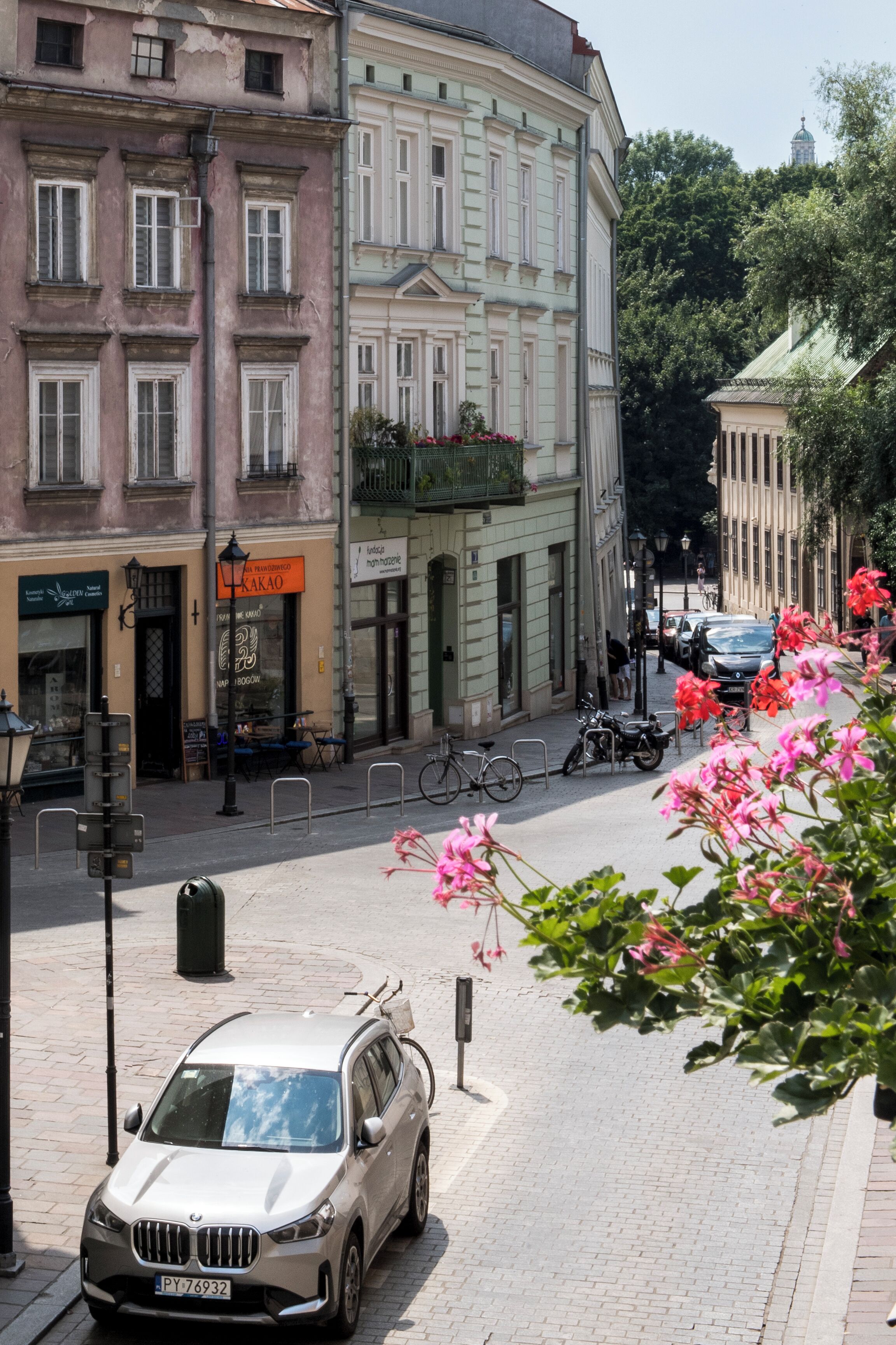 Una vista di strada con un'auto parcheggiata, edifici e una bicicletta.