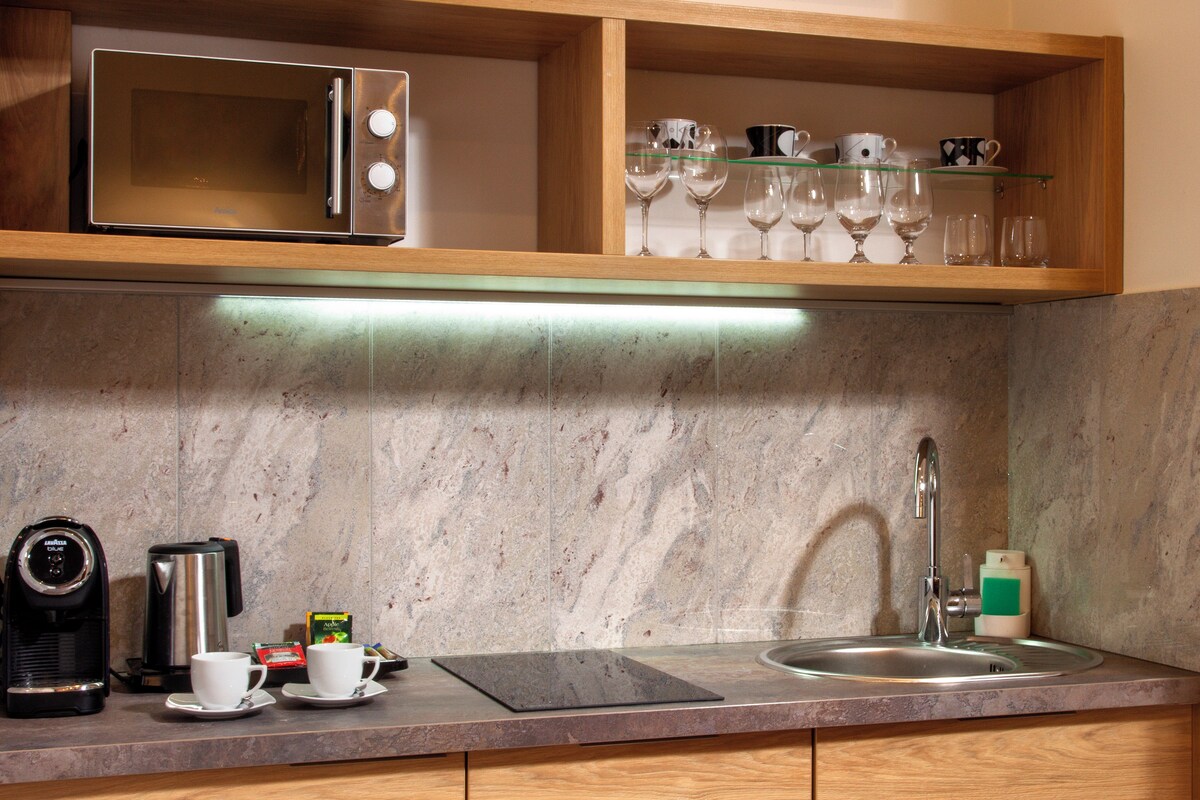 A kitchen with a microwave, coffee maker, and a sink.