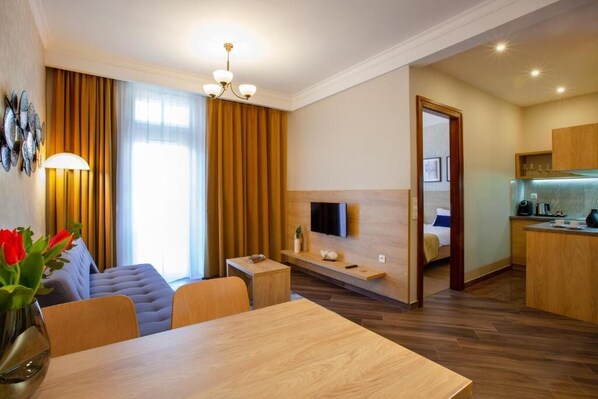 Camera d'albergo moderna con angolo ristoro, angolo cottura e TV a parete.