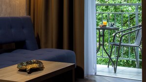 A hotel room with a sofa, a table with a decorative bowl, a floor lamp, and a balcony with a chair and a table. - Portal House Apartments (Kraków)