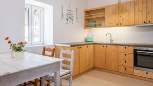 A kitchen with wooden cabinets, a white countertop, a sink, and a built-in oven. - Villa Fioro (Zakynthos)