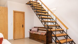 A staircase with wooden steps and black railings, a wooden bench with cushions, and a closed wooden door. - Villa Fioro (Zakynthos)