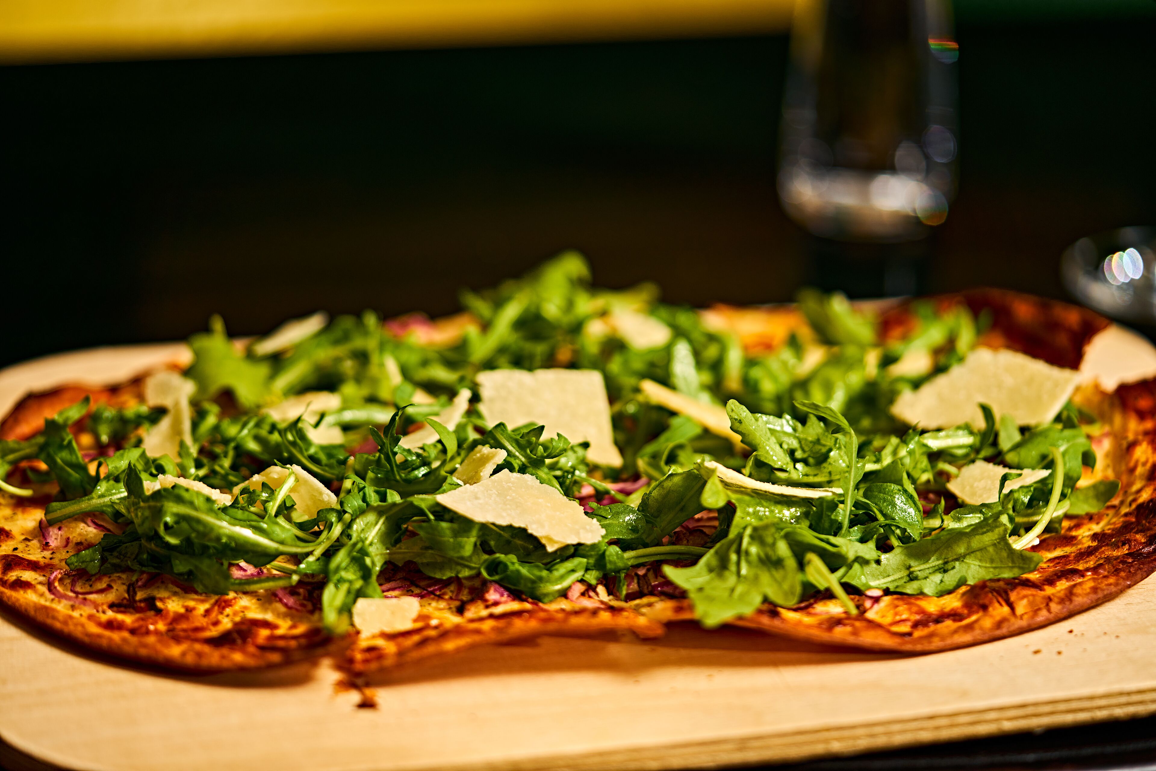 Una pizza con verduras y queso sobre una tabla de madera.