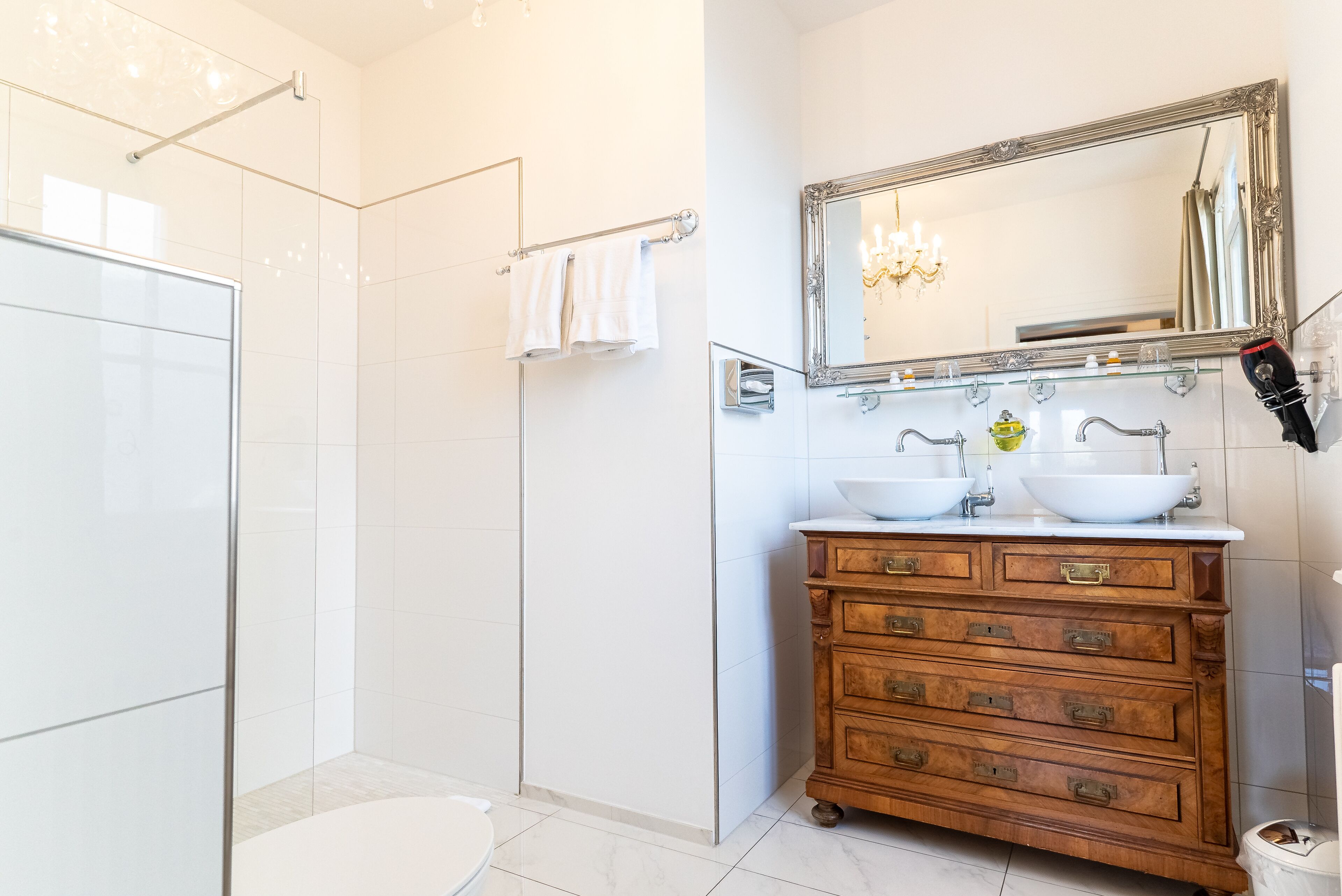 A modern bathroom with a walk-in shower, a vanity with two sinks, and a large mirror above the vanity.
