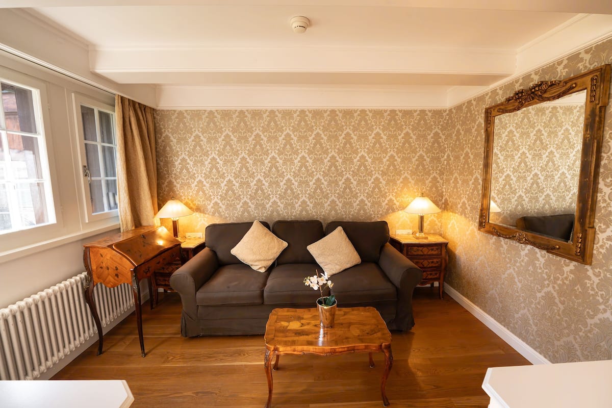 A living room with a sofa, two lamps, a wooden coffee table, and a radiator.