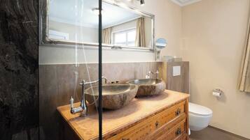 Ein Badezimmer mit einem Holzbadezimmerschrank, zwei Waschtüben, einem großen Spiegel und einer Toilette.