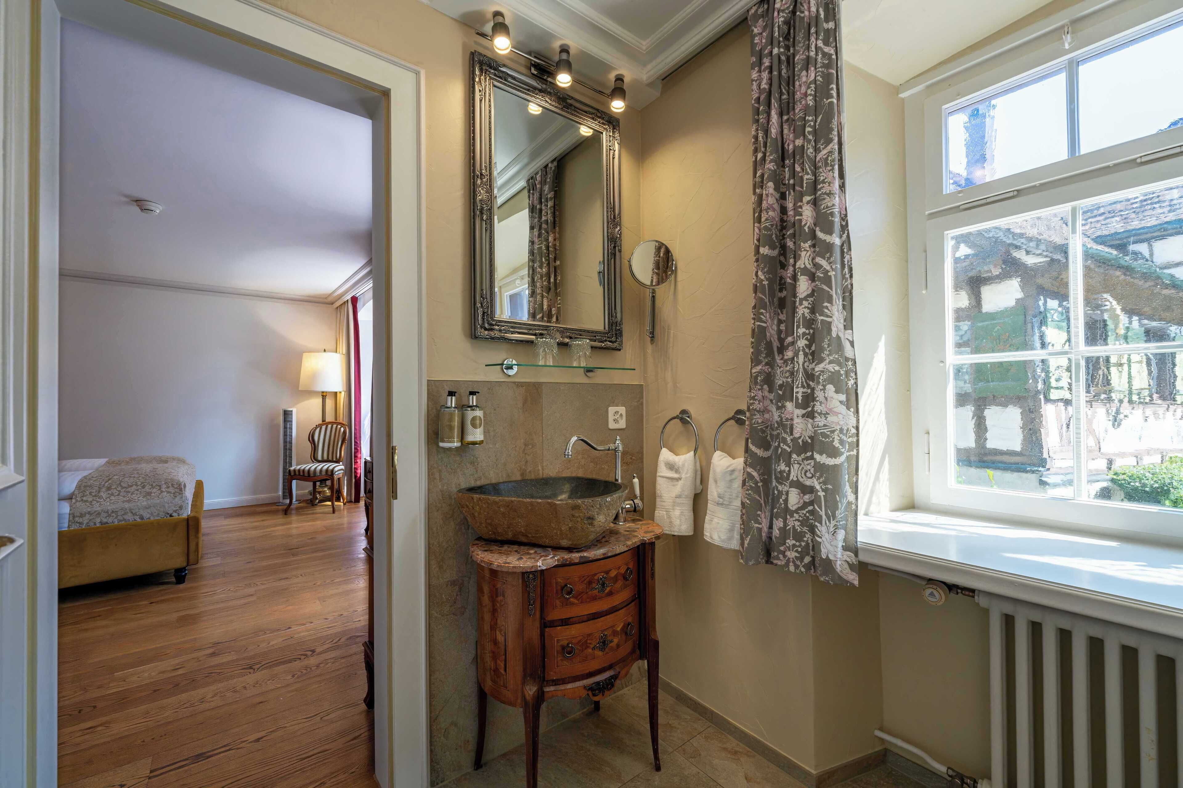A bathroom with a wooden vanity, a large mirror, and a window with a view of buildings.