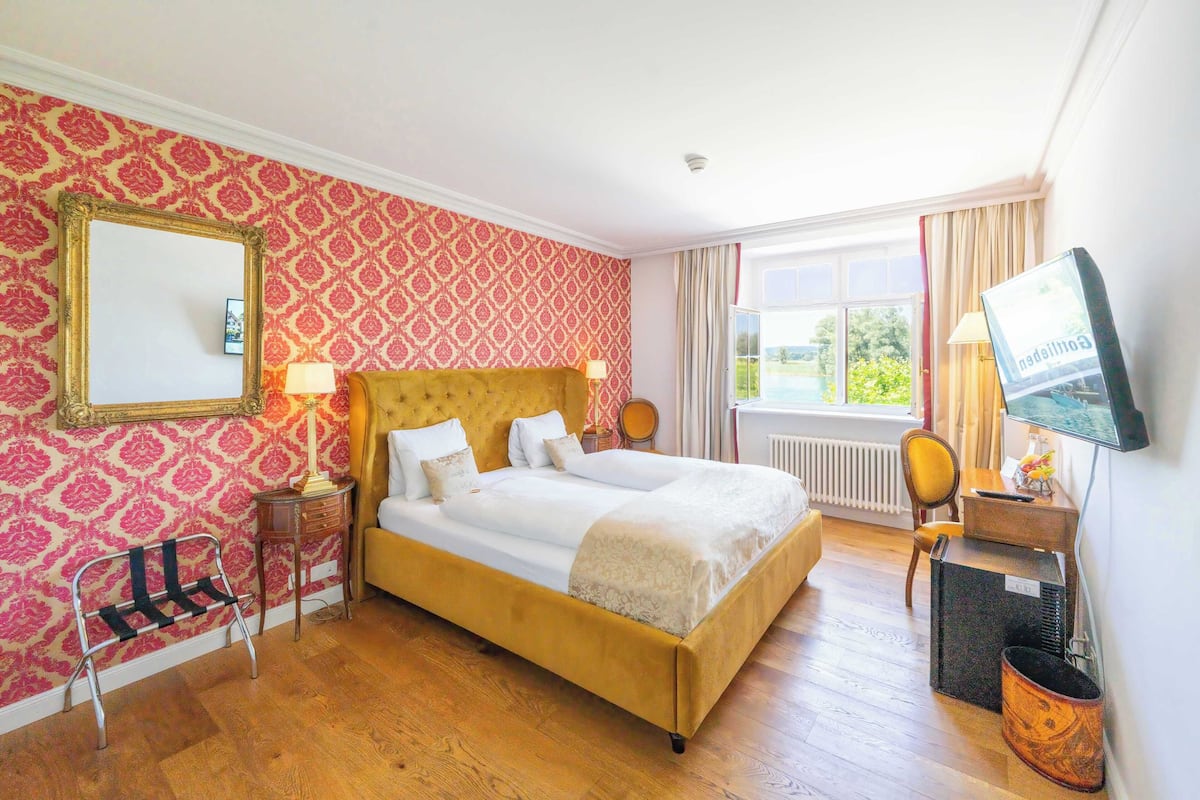 A hotel room with a large bed, a television, and a window with curtains.