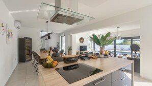 Une cuisine moderne dotée d’un îlot central, d’un four encastré et d’une verrière.