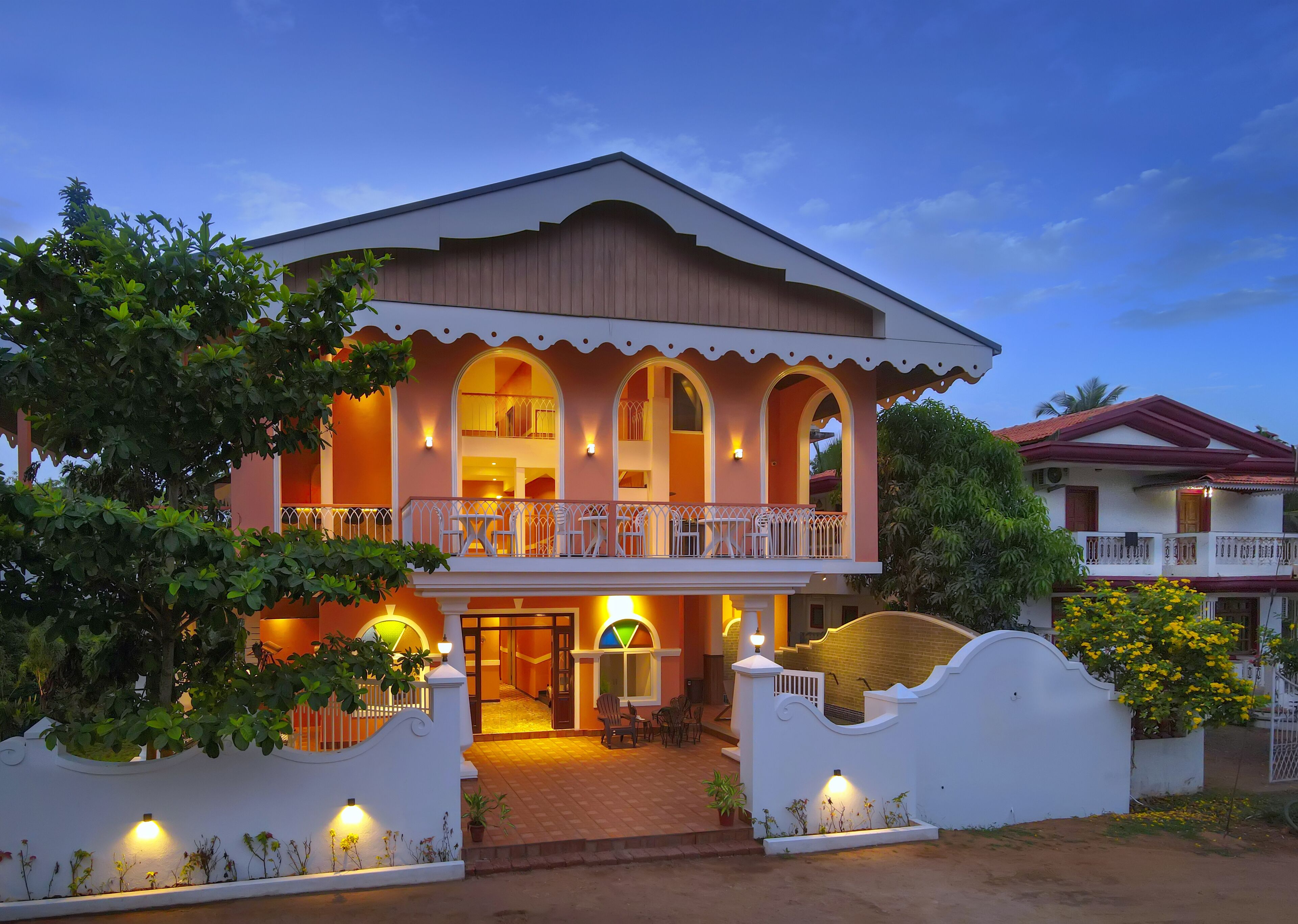A two-story building with a balcony, arched windows, and a gated entrance.