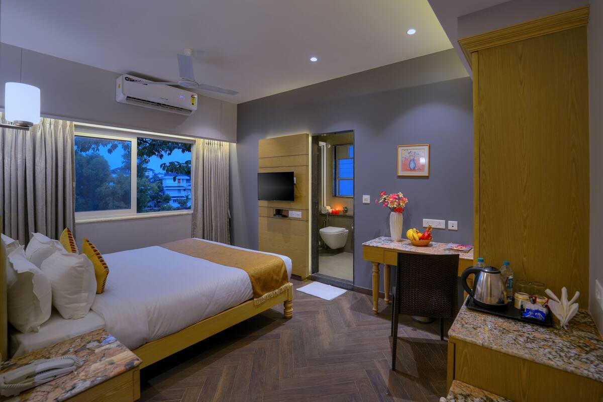 Habitación de hotel con cama, escritorio, silla, baño y vistas al exterior.