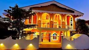 A two-story building with a balcony and arched windows, surrounded by a white wall with a gate. - Foxoso Vega, Colva, Goa (Margao)