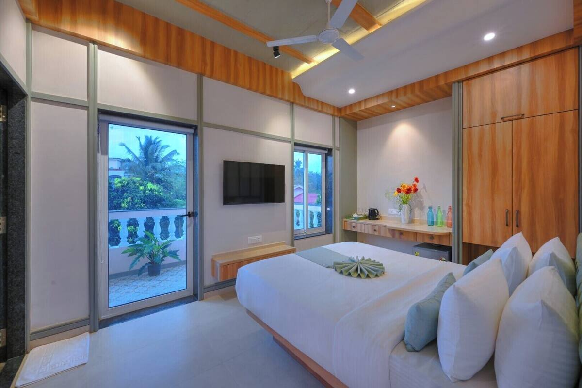 Un dormitorio moderno con una cama grande, puertas corredizas de vidrio a un balcón, un televisor montado y muebles de madera.