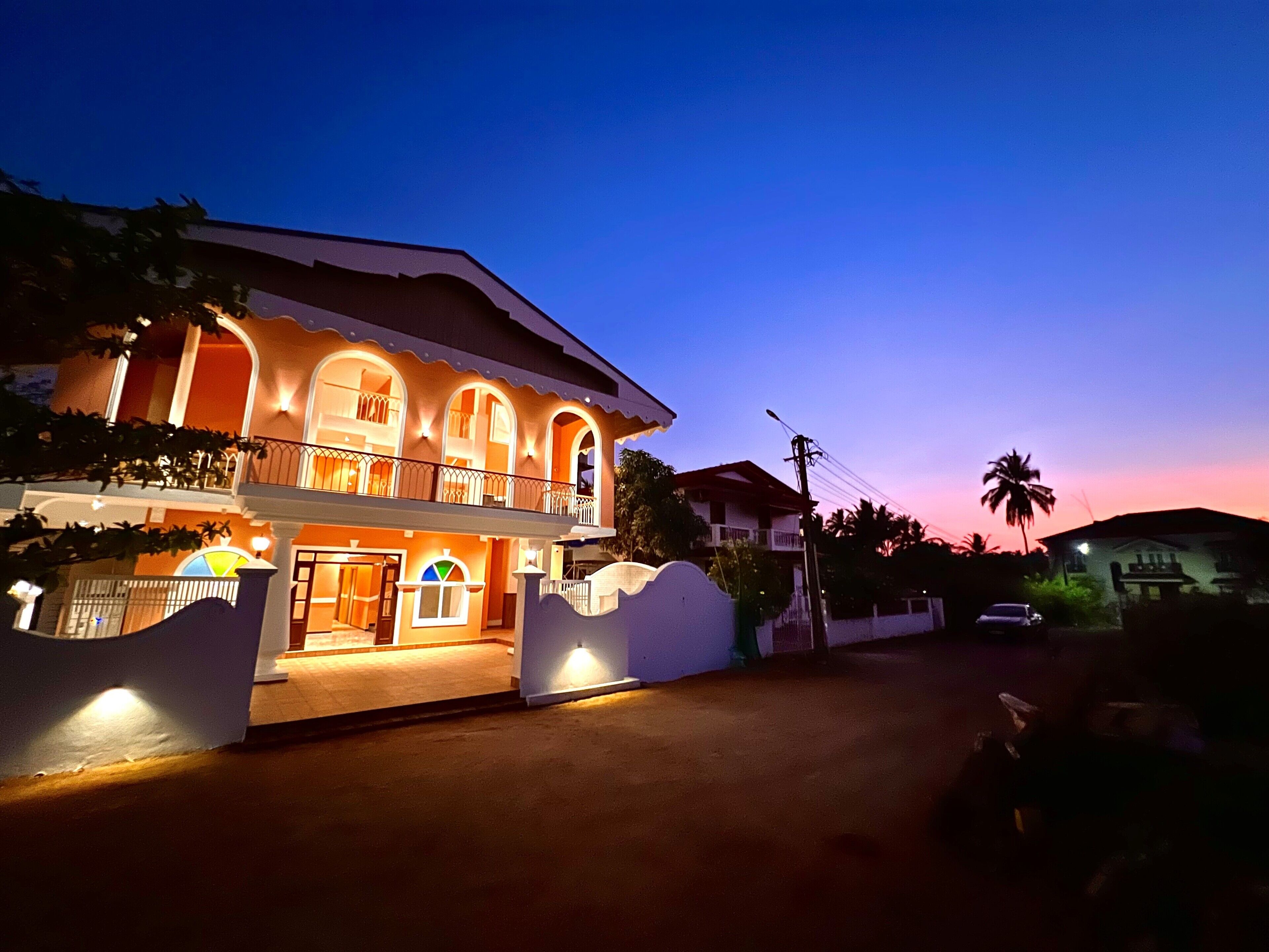A two-story building with a balcony and a well-lit entrance.