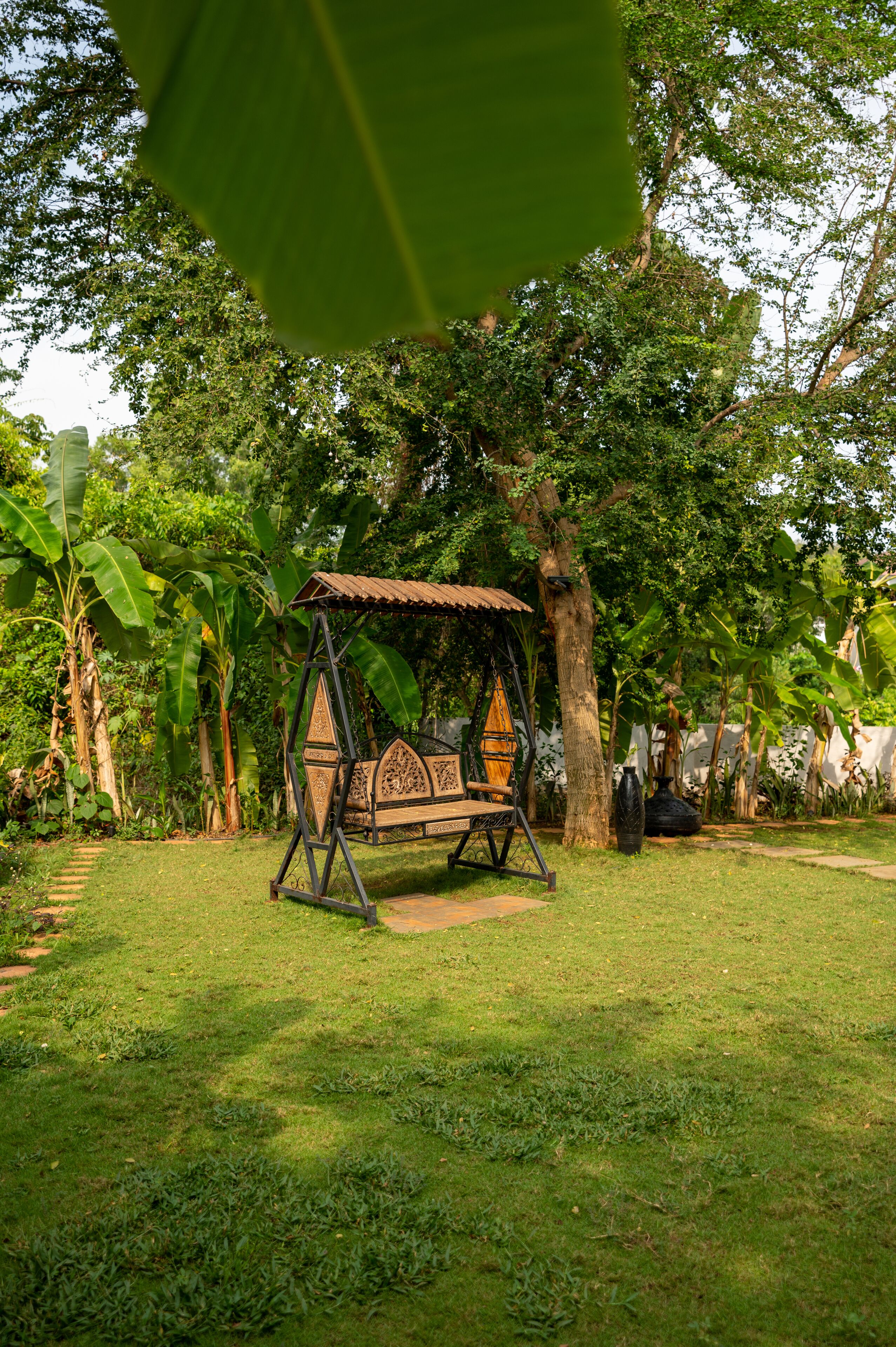 A swing set in a lush garden with a wooden bench and decorative elements.