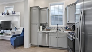 A modern kitchen with grey cabinets, a stainless steel refrigerator, and a built-in dishwasher.