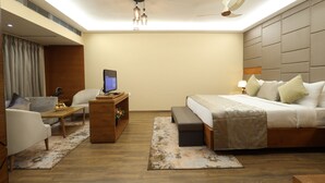 Ein modernes Hotelzimmer mit Bett, Schreibtisch, Sessel, Sofa und Deckenventilator.