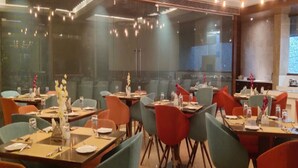 Ein Restaurant mit mehreren Tischen und Stühlen, einem modernen Interieur und Blick durch große Fenster.