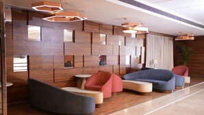 Eine moderne Lobby mit Holzwandverkleidung, einer blauen Couch, roten Sesseln und einem kleinen Tisch.