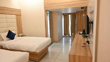 Quarto de hotel com cama, escrivaninha e televisão.