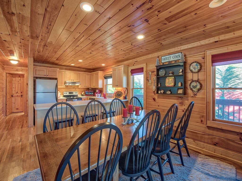 A wooden cabin interior with a dining area, kitchen, and a sign reading "SWEET CORN".