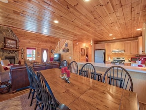 Un intérieur de chalet en bois spacieux, comprenant un coin repas, une cuisine et un salon.