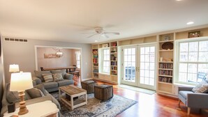 Un salon spacieux comprenant un canapé, une table basse, des poufs et une bibliothèque.