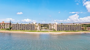 A beachfront hotel with multiple buildings, a beach, and clear skies.