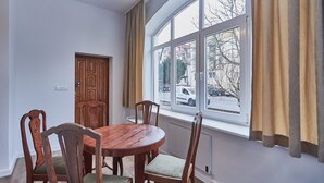 Ein Essbereich mit einem runden Holztisch, Stühlen, einem Fenster mit Vorhängen und einer Tür.