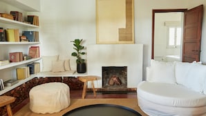 Ein Wohnzimmer mit einem weißen Sofa, einem Kamin, einem Bücherregal und einem großen Gemälde.