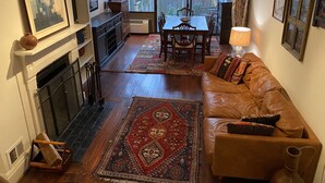 A cozy living room with a fireplace, a dining area, and a view of the backyard.