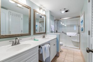 A bathroom with two sinks, a shower, and a toilet.