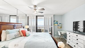 A bedroom with a bed, a desk, a television, and a balcony with a view. - Recently Renovated Oceanfront Condo, Private Resort +Free Attraction Tickets! (Myrtle Beach)