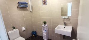A bathroom with a toilet, sink, and a small shelf with folded towels. - Lcp 1 (Genting Highlands)