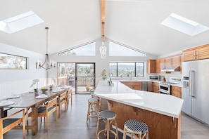 Een moderne keuken met een groot eiland, houten kastjes en een dakraam.