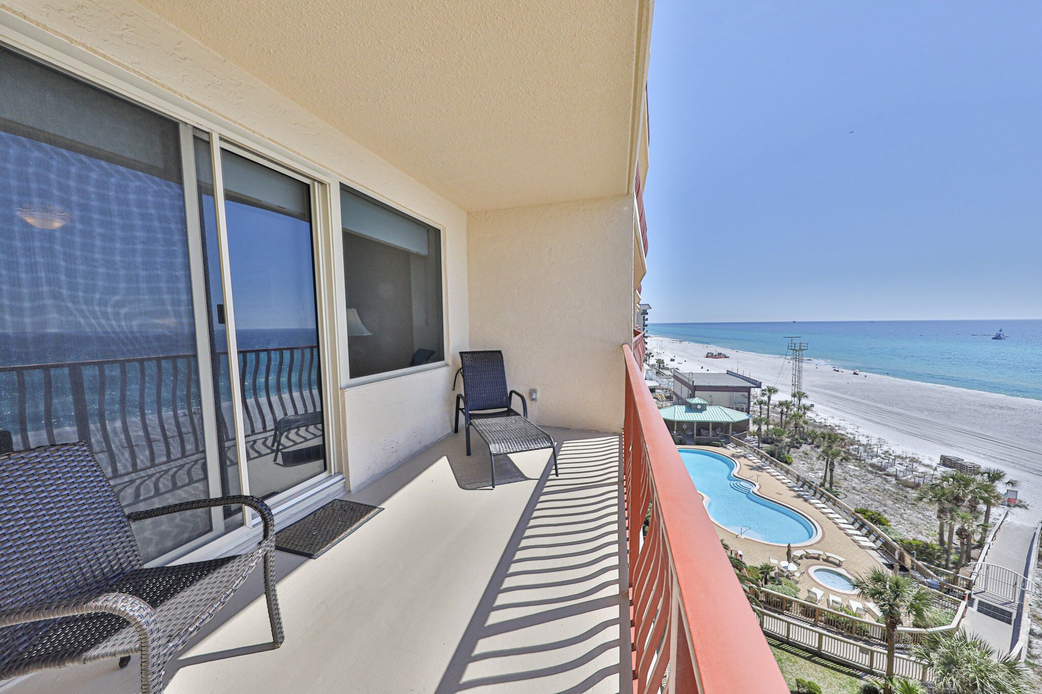 Ein Balkon mit Blick auf den Strand, ein Pool und ein Stuhl.