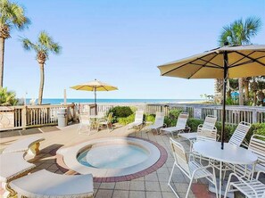 Relax in a serene oceanfront setting with a hot tub and comfortable lounge seating.