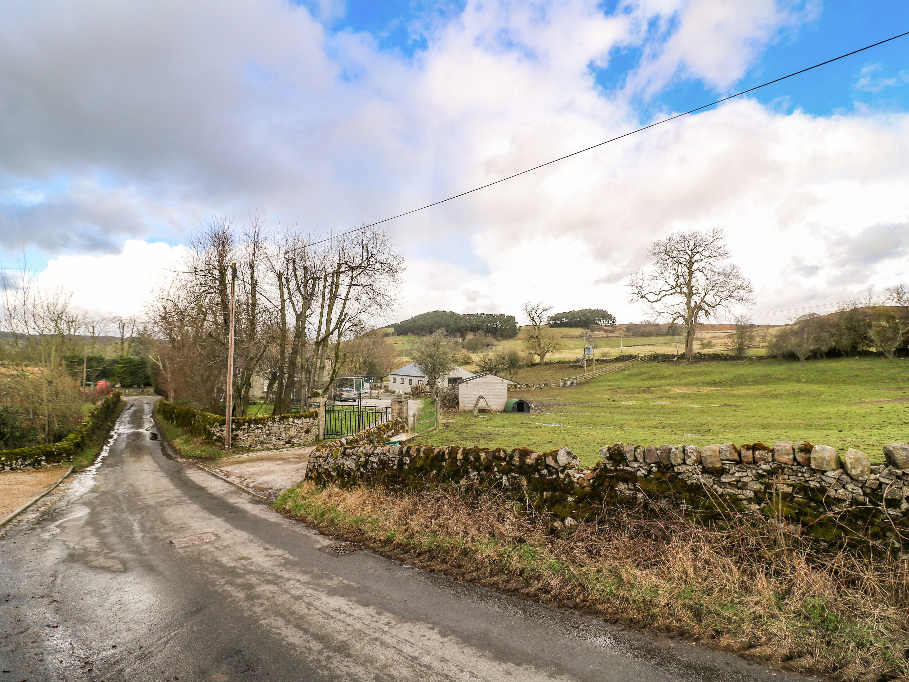 A rural road with stone walls and a small building.