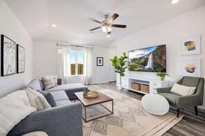 A modern living room with a sofa, armchair, coffee table, and a flat-screen TV.